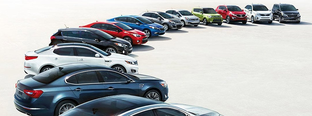 244-a-curved-line-up-of-kia-models-and-builds-parked-on-a-ligh-sun-bleached-stony-pl.png