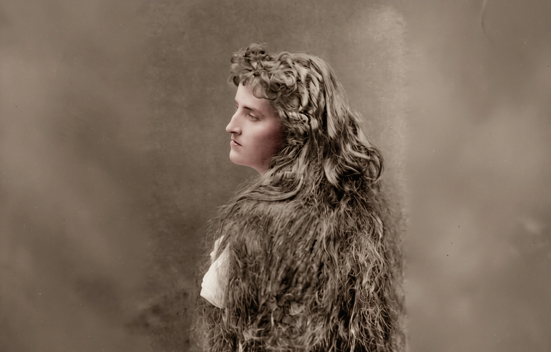 Winnaretta Singer at eighteen, in a studio portrait from 1883. The loose, unbound hair — a deliberate art-portrait convention of the period — signals that she is still unmarried; in four years she would be obliged by her mother to accept Prince Louis de Scey-Montbéliard. The marriage lasted five years before annulment. The hair, by then, was already up.