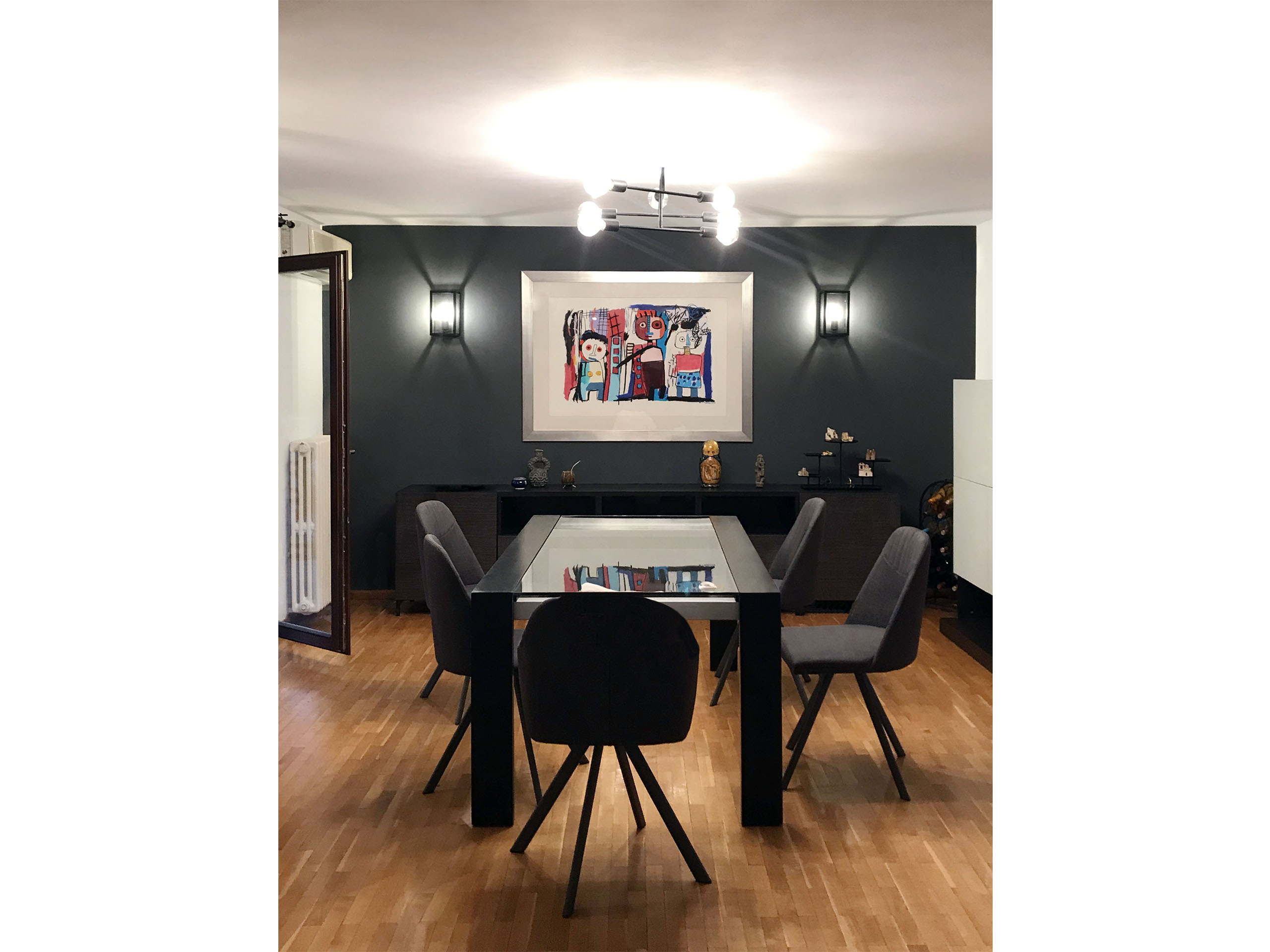 Dining table in front of a dark charcoal wall with bright colorful art standing out