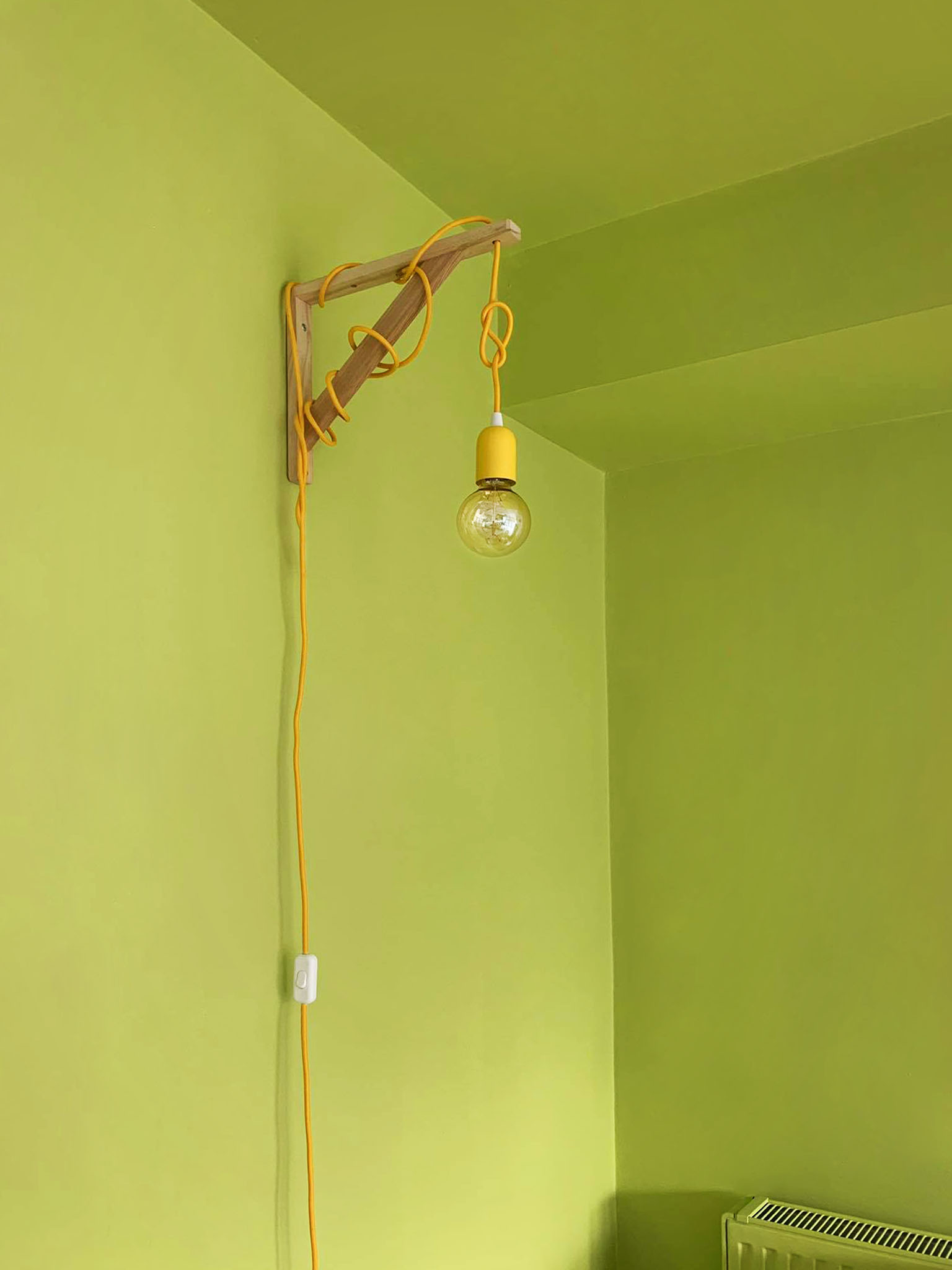 Bright green color block separating the space with a bright yellow hanging cable lamp