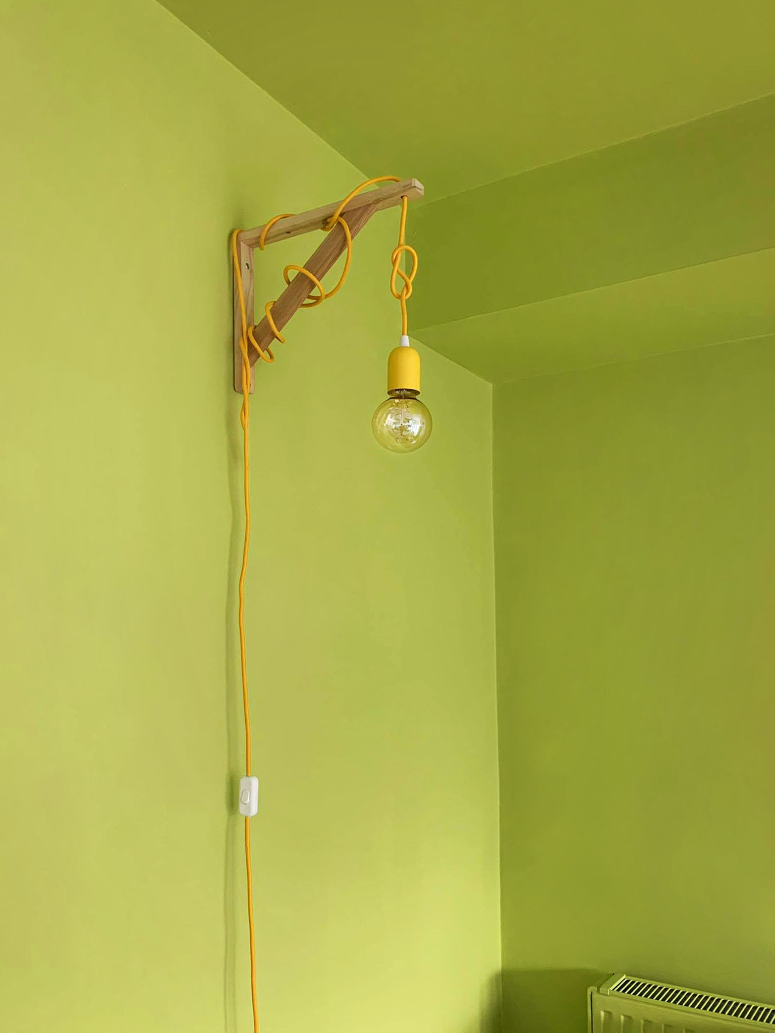 Green Living Room Bright green color block separating the space with a bright yellow hanging cable lamp
