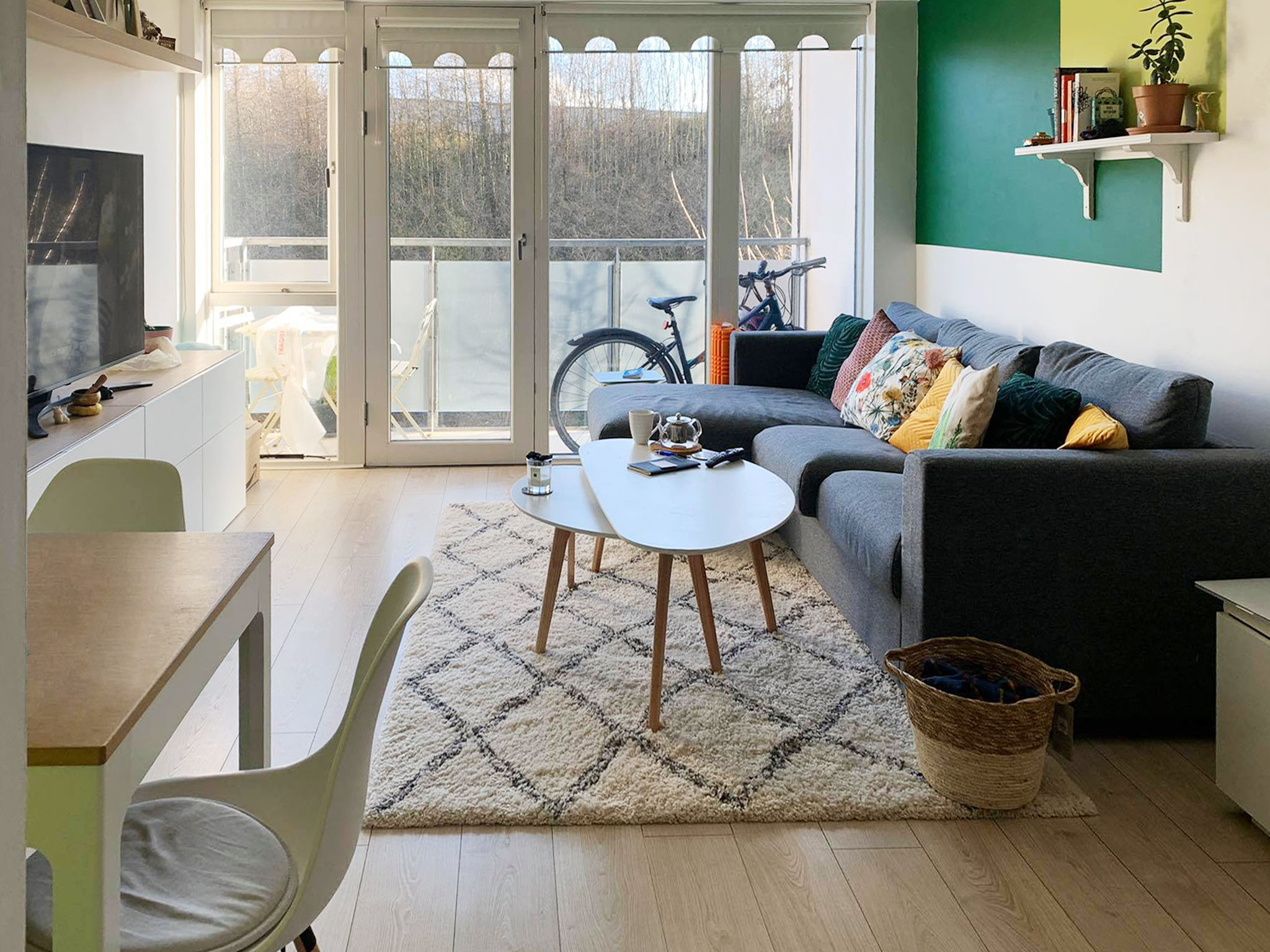 Small cozy living room with neutral furniture and green details