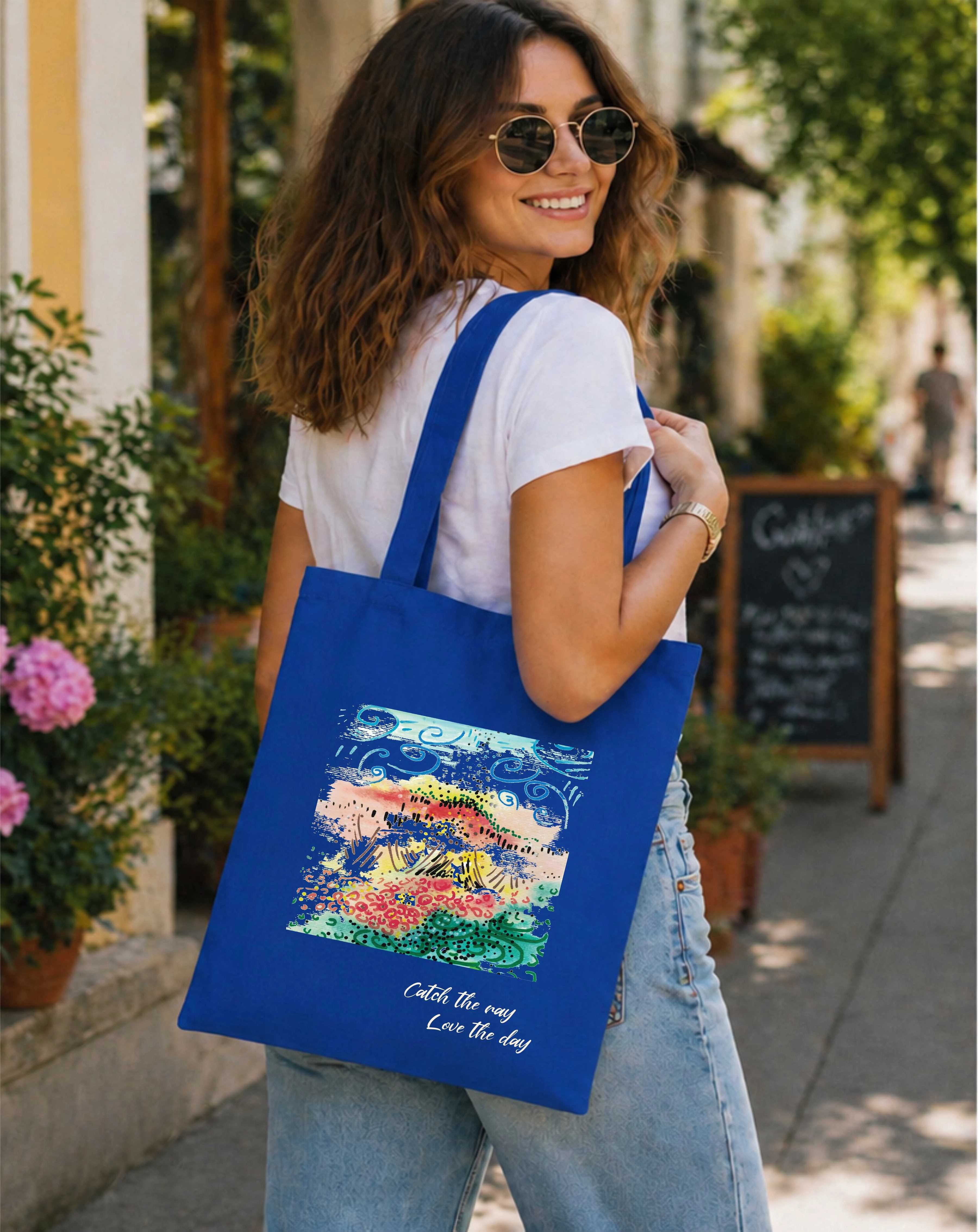 A woman carying blue canvas bag with art print, posing against the street.