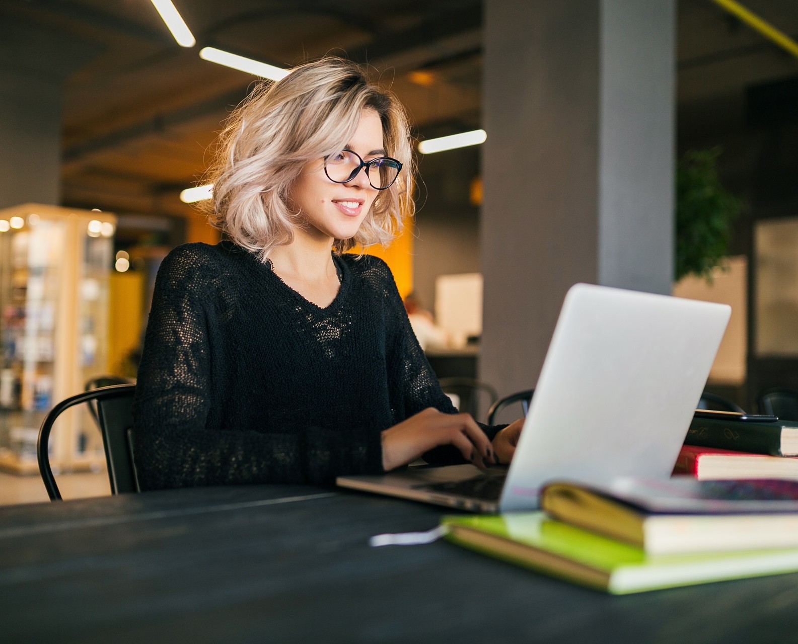 16601585128056-portrait-young-pretty-smiling-woman-sitting-table-black-shirt-working-laptop-co-.jpg