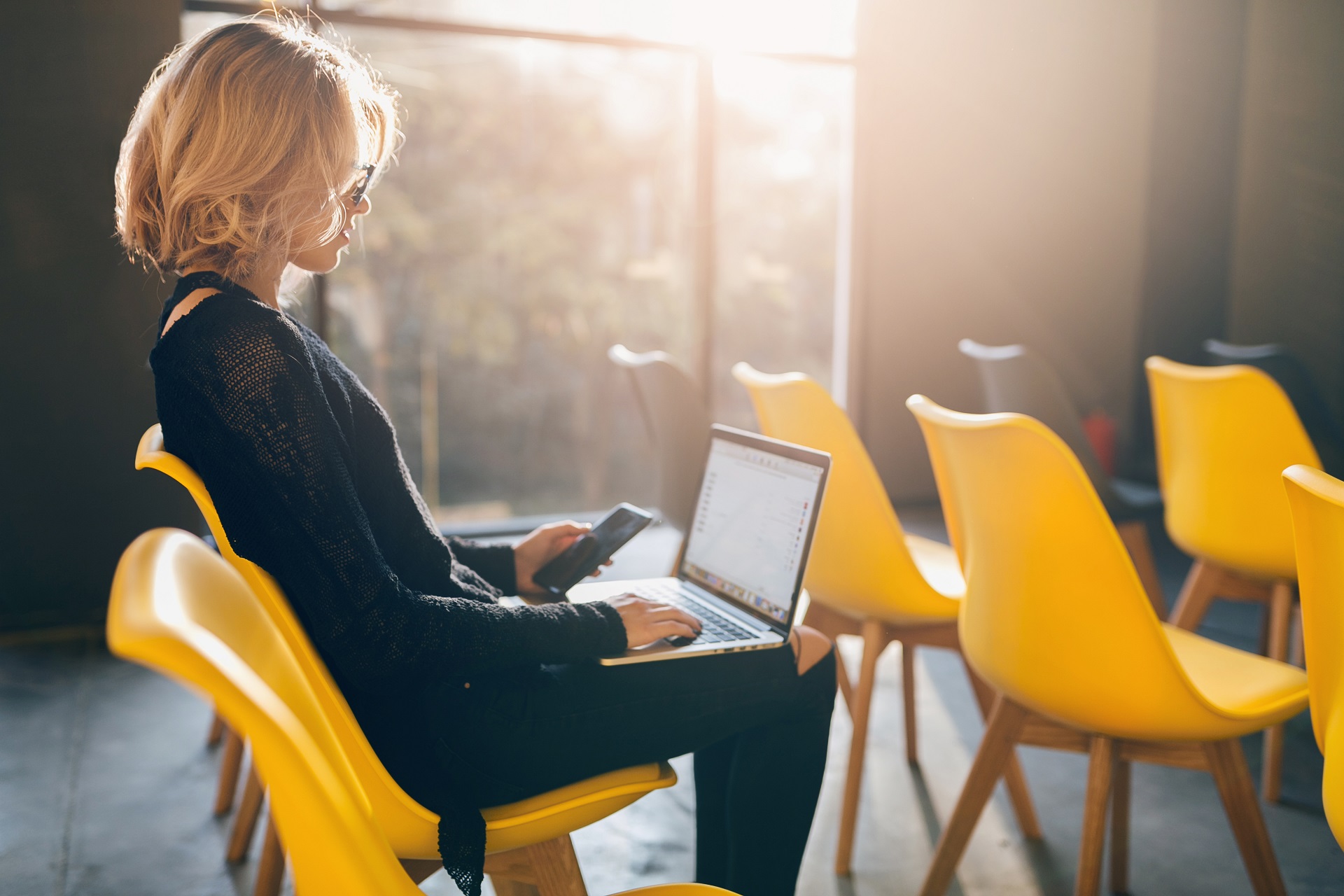 r16-young-pretty-busy-woman-sitting-alone-conference-room-many-yellow-chairs.jpg