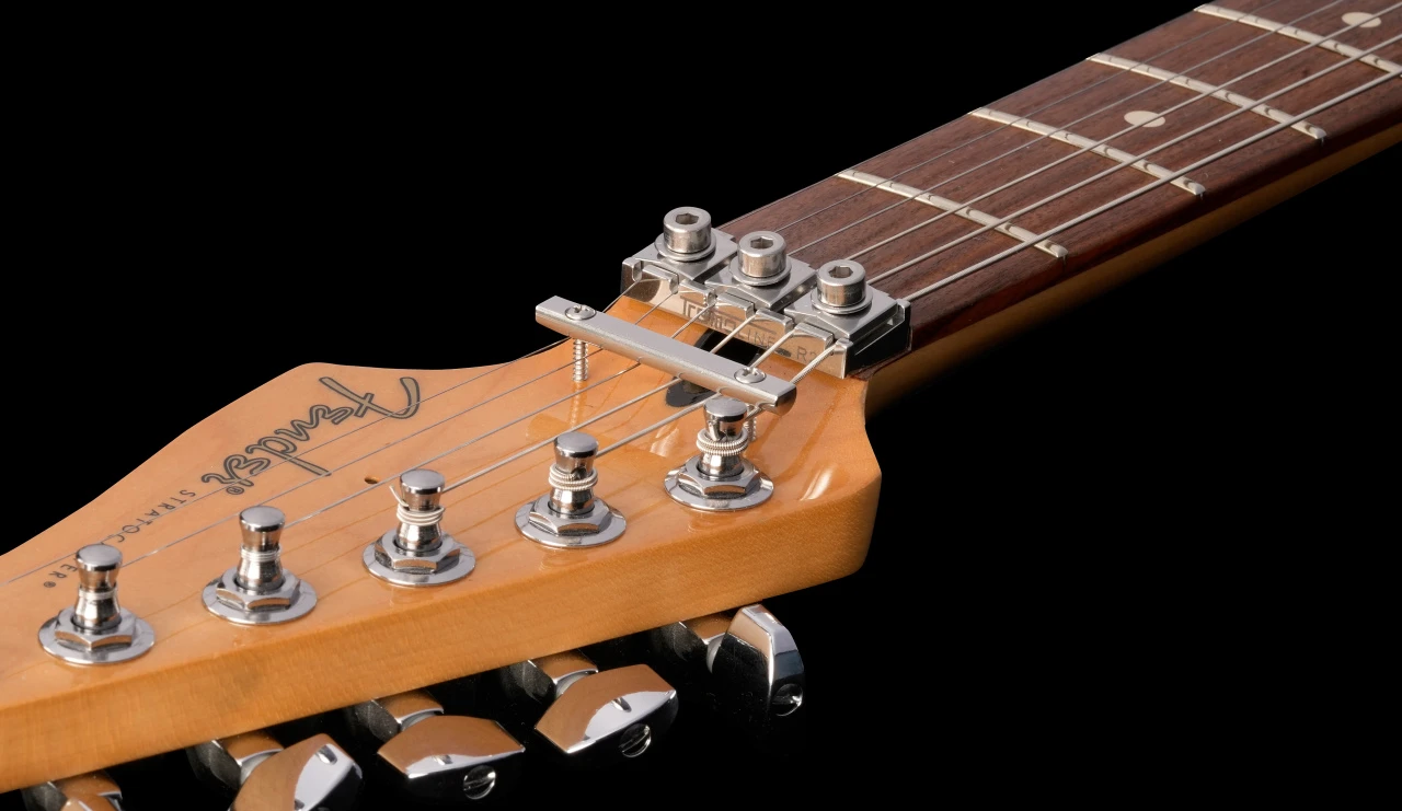 Tremoline-FT36T-guitar-locking-tremolo-1280x741-v05 <img src=”Tremoline-FT36T-guitar-locking-tremolo-1280x741-v05.jpg” alt=”stainless steel guitar locking nut on the guitar neck over the black background”>