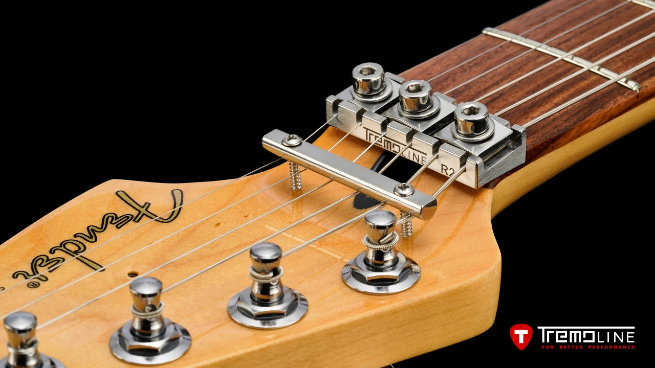 <img src=”Tremoline-guitar-double-locking-tremolo-Fender-Stratocaster-RH-1280x720-J3A.jpg” width="1280" height="720" alt=”Tremoline LN6A locking nut on Fender Stratocaster RH guitar” />